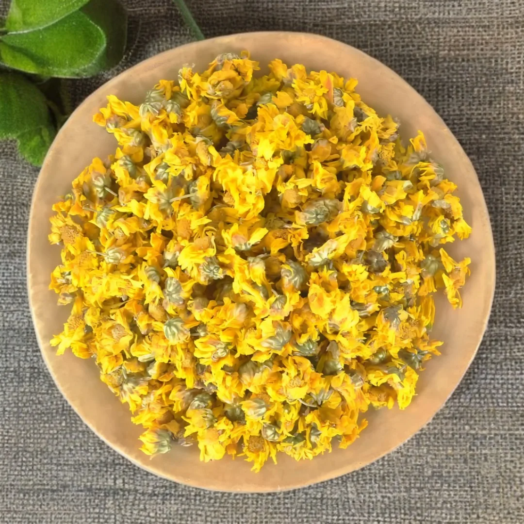 Bowl of dried yellow chrysanthemum flowers for caffeine-free herbal tea on textured surface.
